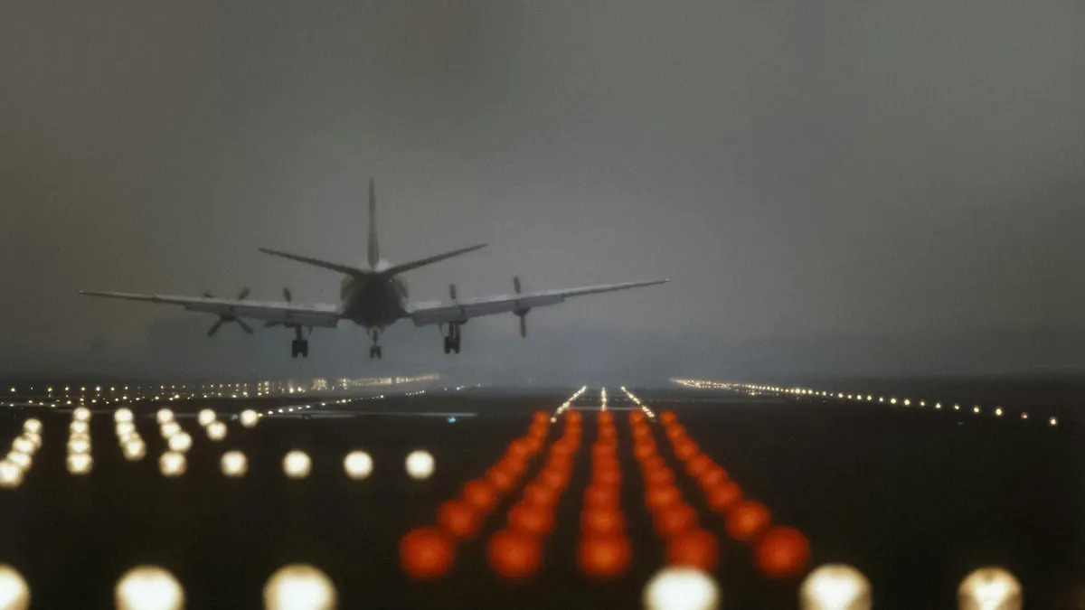 Runway approach lights glowing in fog as a jet lands